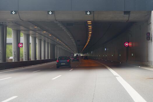 Traffic flows through an urban highway tunnel with clear speed limits on display during daylight hours in an organized infrastructure photo