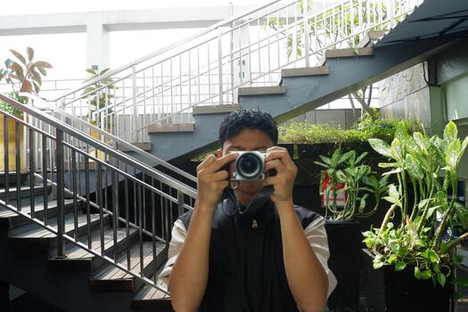 Authentic Portrait of Young Man Taking a Picture with Digital Camera at Stairs photo