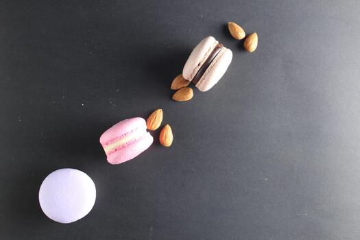 the layout top three macaroons and almond nuts lie on a black background with room for text and with a copyspace. photo