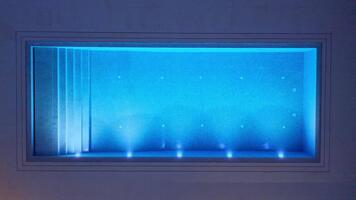 descendente zumbido ver de moderno rectangular nadando piscina a noche iluminado con azul LED luces demostración pasos y submarino Encendiendo modelo concepto de lujo relajación y Noche ambiente video