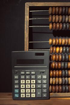 Calculator and abacus on wooden table create contrast between old and new calculation methods photo