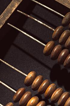 Old wooden abacus with metal rods and beads resting on a dark surface photo