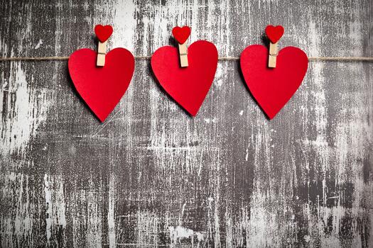 Colorful hearts hang on a twine string against a rustic background in a creative display photo