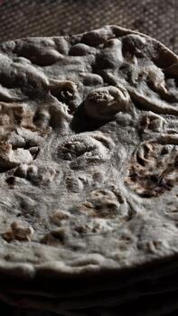 Close-up of a freshly baked flatbread showcasing its rustic texture and artisanal quality, illuminated by soft, diffused lighting to highlight the subtle details photo