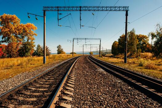 Parallel railway tracks and overhead lines through the forest. autumn photo