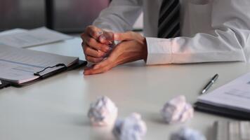 uomo a ufficio scrivania stressato o frustrato, accartocciando carta e il presenza di multiplo spiegazzato carta palle su tavolo. video