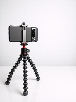 Smartphone mounted on a flexible tripod stand isolated on white background. Mobile photography and vlogging equipment setup. Vertical photo with copy space for text
