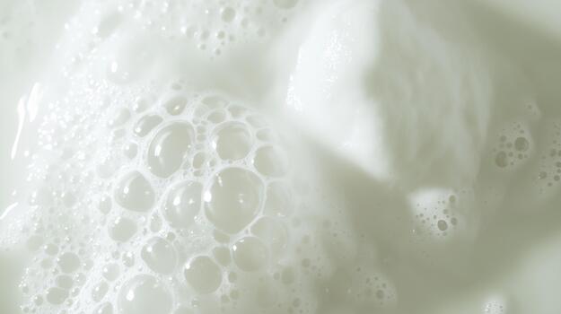 Close-up view of white foam bubbles on a smooth surface, creating a soft and creamy texture, ideal for backgrounds or product displays in culinary or beauty contexts photo