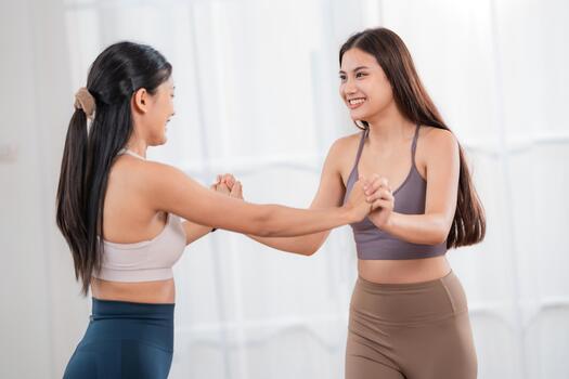 Two friends practice partner exercise in a gym during the day in a bright room with natural light coming through the windows photo