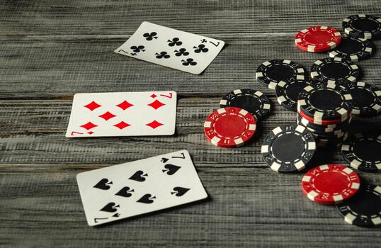 Upon closer inspection, three playing cards, a winning combination of three of a kind, set, can be seen laid out on a rustic wooden table along with chips, creating an exciting atmosphere for the game photo