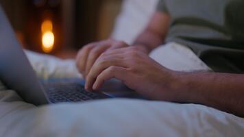 Close up man hands lying in bed typing laptop using computer gadget online technology night working freelance internet web browsing texting chatting unrecognizable business email businessman ecommerce video