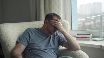 man reflekterande på hans tankar medan Sammanträde förbi en fönster i en mysigt rum under en molnig eftermiddag video