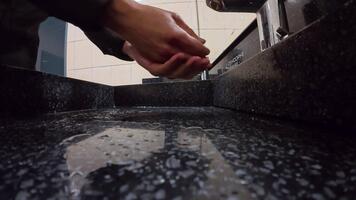 A man washes his hands under a sensor-controlled faucet in a clean setting. video