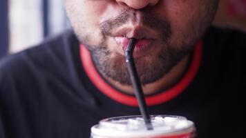 man drycker kall dryck använder sig av en sugrör i Kafé miljö video
