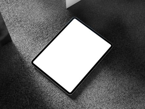 Blank tablet screen positioned on a dark background with soft shadows and minimal texture. photo