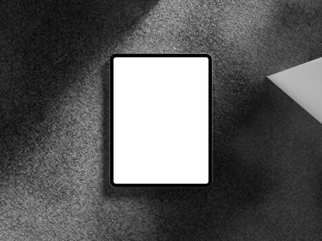 Top view of a tablet screen on a dark background with angled shadows and geometric shapes. photo
