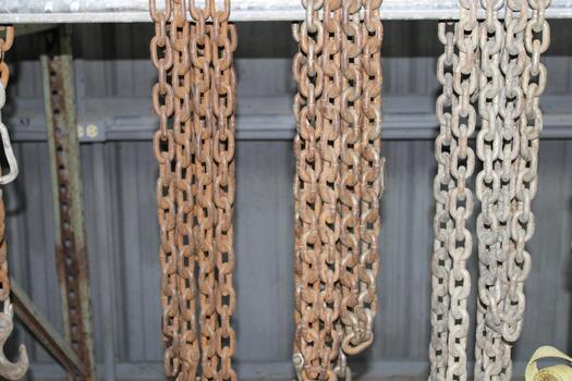 Three Sets Of Metal Chains Hanging In A Workshop photo