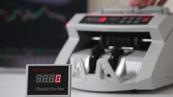 conto contatore schermo con rosso numeri in crescita velocemente. mano mette noi dollari in macchina per contare a fondale nel sfocatura. video