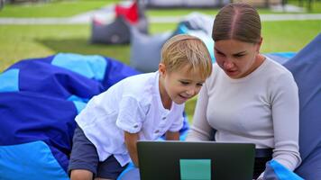 Showing something interesting at computer. Mom and son look at the screen with interest and smile. Blurred backdrop. video