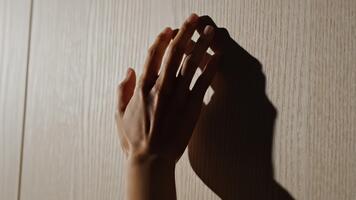 Seeking connection, a gentle hand reaches out to touch a textured wooden surface in soft, diffused light, creating a sense of longing and anticipation video