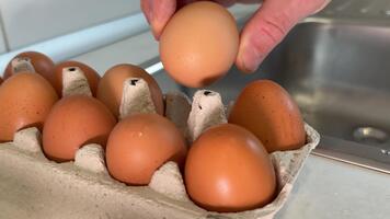hand väljer ägg hand väljer färsk brun ägg från en gul plast spjällåda på en mataffär. de ägg är anordnad på en kartong ark, och en handla vagn är synlig i de bakgrund. video