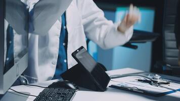 un' medico è Lavorando su un' computer mentre un altro persona è in piedi Il prossimo per lui video