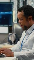 vertical técnico en oficina resolviendo Tareas con artificial inteligencia llm chatbot respondiendo avisos africano americano hombre a trabajo utilizando ordenador personal a interactuar con grande idioma modelo programa, cámara si video