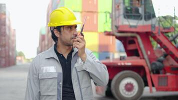 i en livliga behållare lager, ingenjör arbetstagare engagerar i kvalitet kontrollera checkar och kommunicerar med kollegor via telefon och radio, sedan ser på kamera och leende självsäkert. video