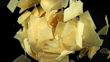 parmesan ost flingor flyga uppåt på en svart bakgrund. filmad på en hög hastighet kamera på 1000 fps. hög kvalitet full HD antal fot video