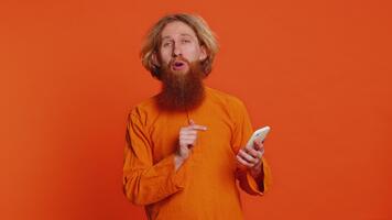 caucasico uomo uso smartphone digitando inviare su ragnatela, navigazione ricerca, dipendenza di sociale reti, positivo applicazione gioco feedback, raccomanda Wi-Fi cellulare connessione, mostrando su arancia sfondo video