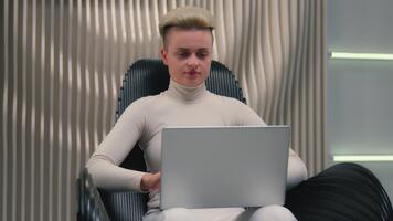 Caucasian calm woman girl female user typing laptop sitting in chair pc computer in white studio futuristic hacker coder gamer lady using cyber computer software tech online network connection work video