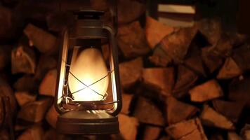 värma glöd av ett gammaldags lykta belysande en stack av ved i en rustik miljö. video
