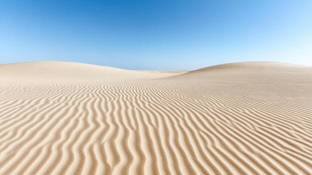 Sand dune ripple pattern under clear blue sky with serene light photo