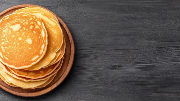Golden pancake stack on wooden plate with dark textured background, appetizing breakfast scene photo