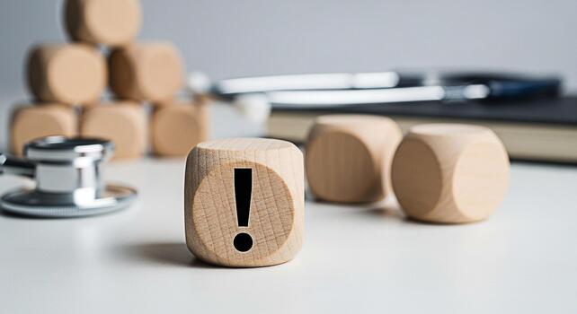 Wooden dice displaying an exclamation mark on a white surface symbolizing a health warning or medical alert in a clinical setting creating a sense of urgency and caution for potential health risks photo