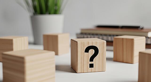 Wooden blocks displaying a question mark on a white desk surrounded by office supplies representing uncertainty and the search for answers in a professional environment photo