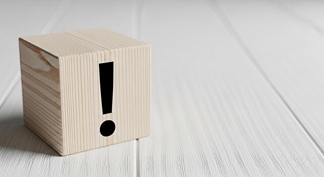 Wooden cube displaying an exclamation mark on a white wooden surface symbolizing attention warning and the importance of information in a clean and minimalist environment photo
