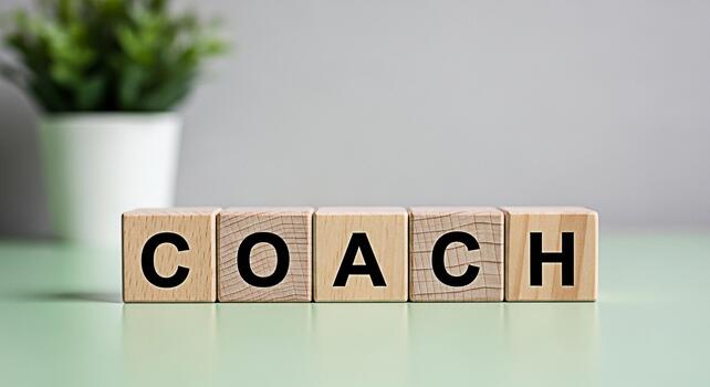 Wooden blocks spelling COACH on a light green surface symbolizing guidance and mentorship in a minimalist setting promoting personal and professional development with a focus on growth and success photo