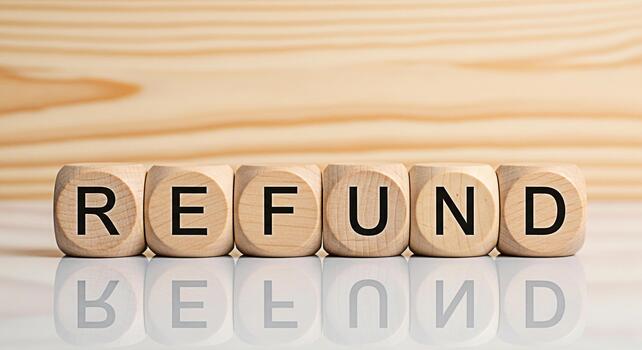 Wooden blocks spelling REFUND on a reflective surface against a light wood backdrop symbolizing financial reimbursement and customer satisfaction in a business context conveying trust and reliability photo
