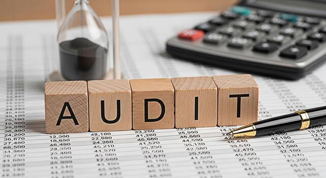 Audit in Progress Wooden blocks spelling AUDIT on financial statements with calculator pen and hourglass representing financial review and time management in a business environment photo