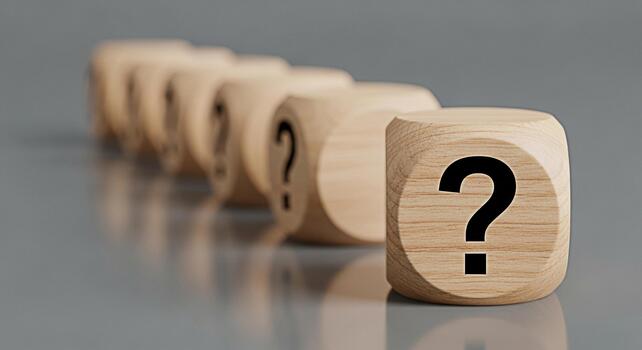 Wooden dice displaying question marks in a row on a gray surface symbolizing uncertainty inquiry and the search for answers in business education or personal development contexts photo