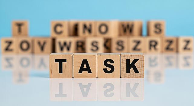Wooden blocks spelling out TASK on a reflective surface symbolizing focus and determination in a bright minimalist setting conveying a sense of productivity and achievement photo