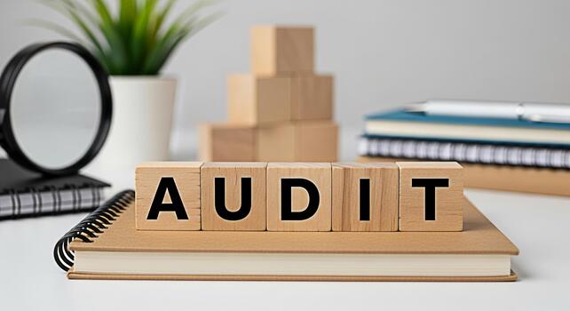 Wooden blocks spelling AUDIT rest on a notebook in a bright office setting symbolizing financial review accuracy and the importance of meticulous examination for business success and regulatory compli photo