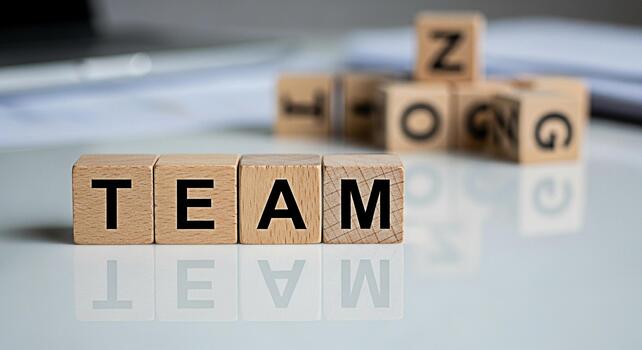 Wooden blocks spelling TEAM and STRONG on a reflective white surface representing collaboration and unity in a business environment fostering a sense of teamwork and achievement photo