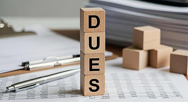 Wooden blocks spelling DUES on a financial report with pens representing financial obligations and responsibilities in a business environment creating a sense of accountability and urgency photo