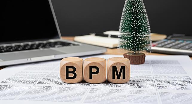 Wooden blocks displaying BPM on a desk with a laptop calculator and Christmas tree representing business process management in a festive office environment symbolizing efficiency and strategic plannin photo