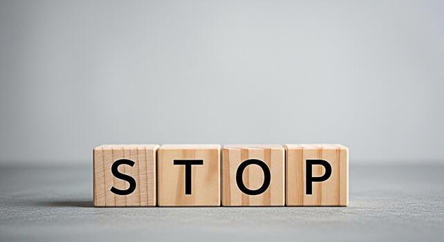 Wooden blocks spelling STOP on a gray surface conveying a message of caution and control ideal for themes of safety prevention and decisionmaking in a minimalist and impactful setting photo
