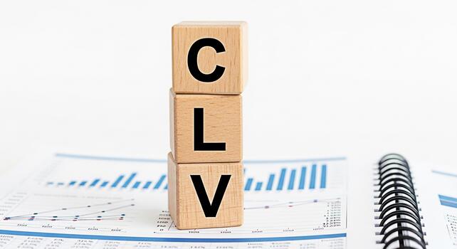 Wooden blocks spelling CLV resting on financial reports in a bright clean office environment representing Customer Lifetime Value and strategic business growth with a focus on datadriven insights photo