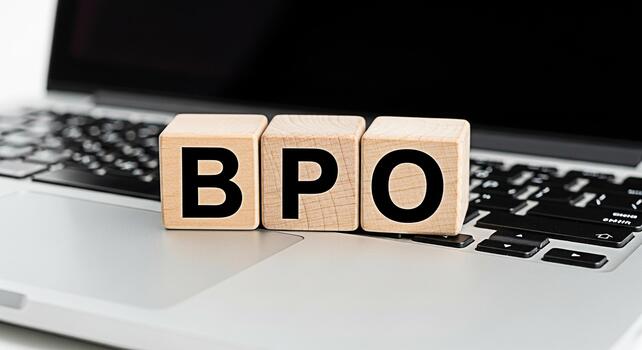 de madera bloques ortografía bpo descansando en un ordenador portátil teclado en un brillante oficina ajuste simbolizando negocio proceso outsourcing y eficiente flujo de trabajo soluciones para moderno empresas foto