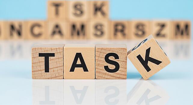 Wooden blocks spelling out TASK on a reflective surface with other lettered blocks in the background symbolizing focus and determination in a business or educational setting conveying a sense of purpo photo
